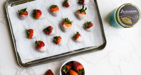 Strawberries dipped in coconut butter on a baking tray