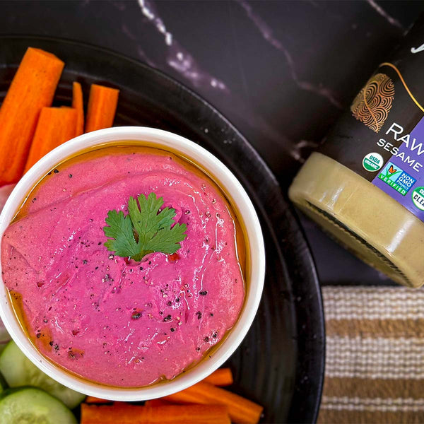 Bright pink beet hummus surrounded by crudités.