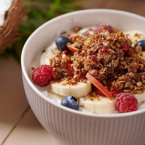 Fresh fruit on top of granola and yogurt in a white bowl.
