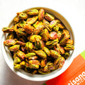 White bowl filled with green and orange roasted pistachios on a white background