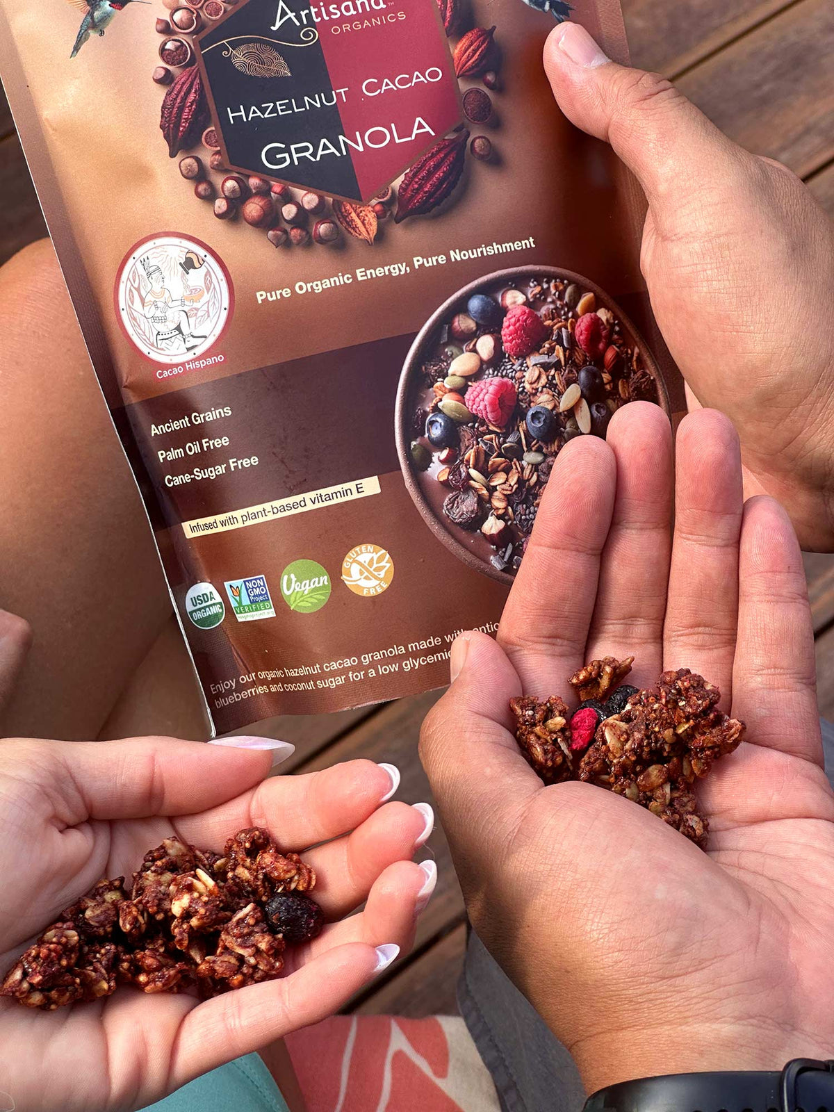 Hazelnut Granola clusters being held in 2 persons hands