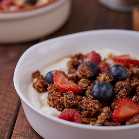 Bowl of granola with yogurt and berries on a wooden surface